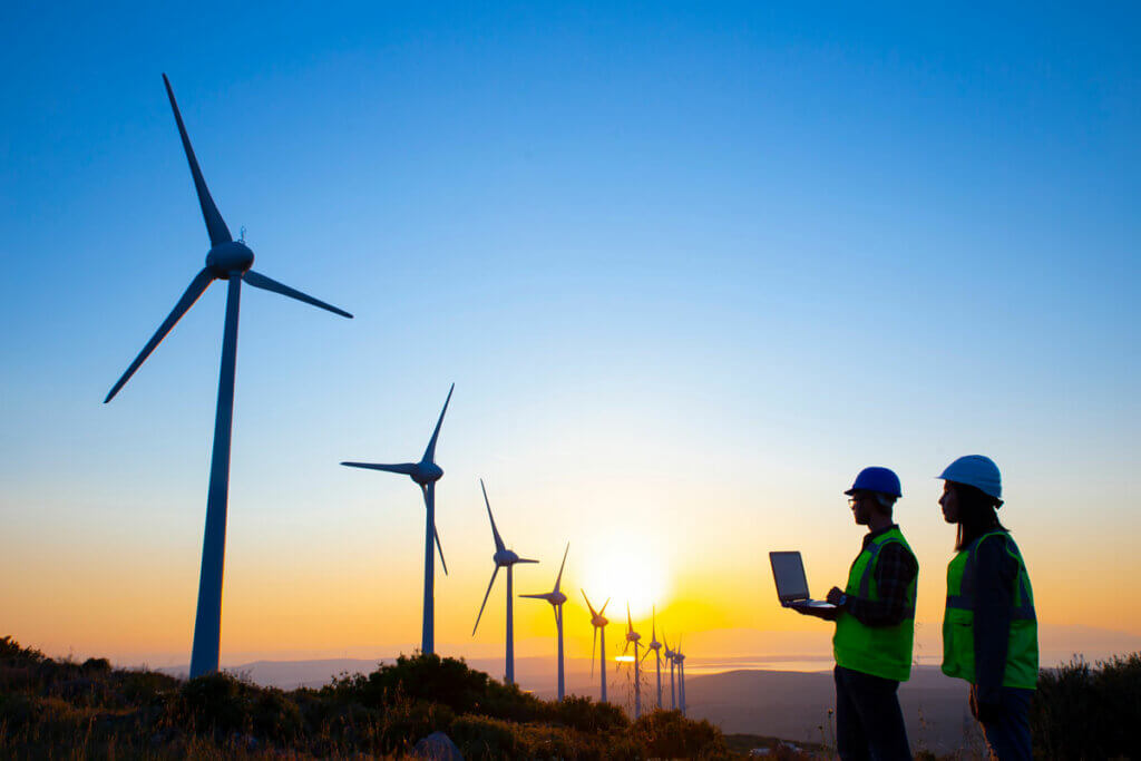 Energy-Young-engineer-team-working-in-wind-turbine-farm-at-sunset-stock-photo